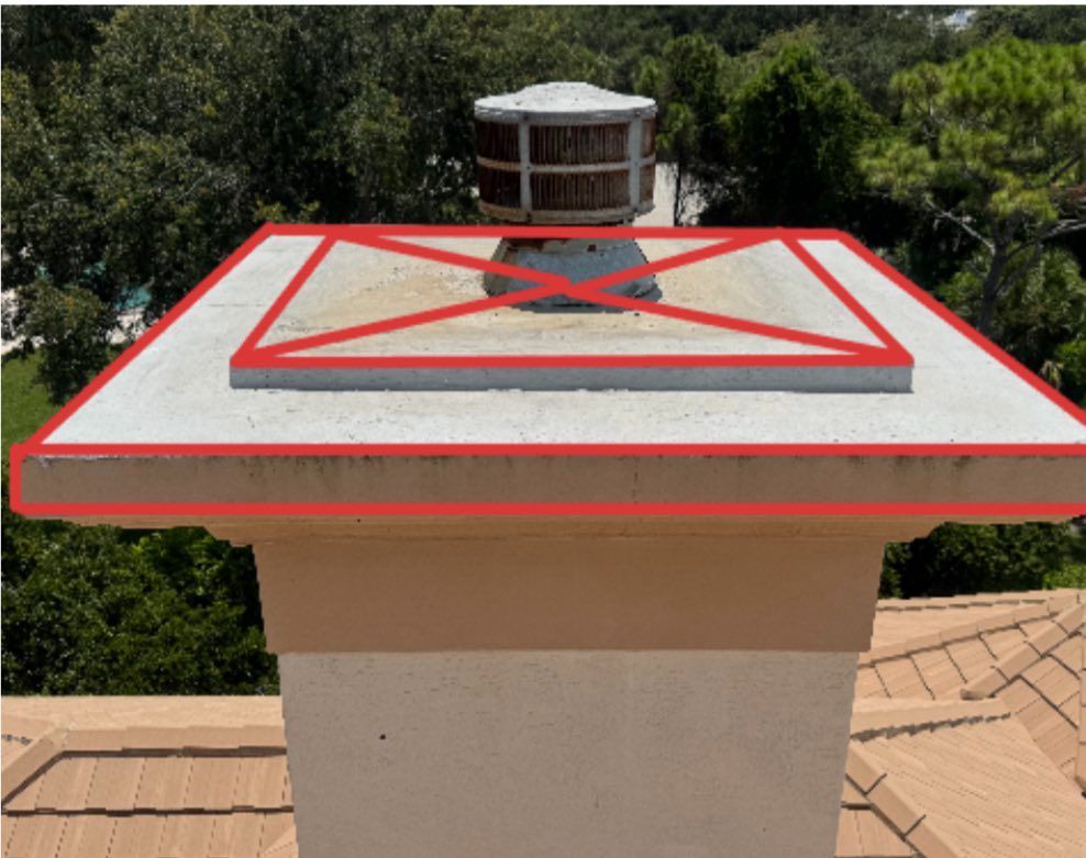 Rooftop vent cap with a red protective frame on a beige chimney against trees and sky