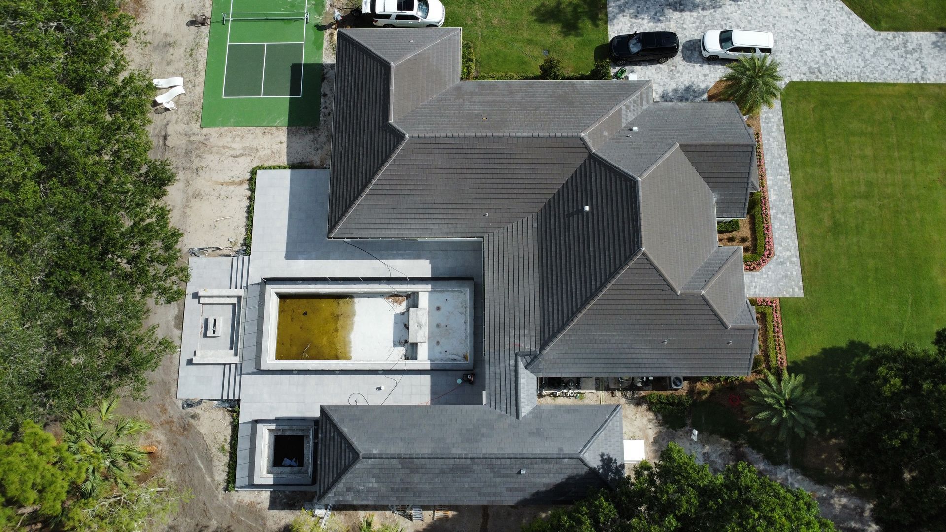 Aerial view of a gray-roofed house with a central courtyard and surrounding green yard.