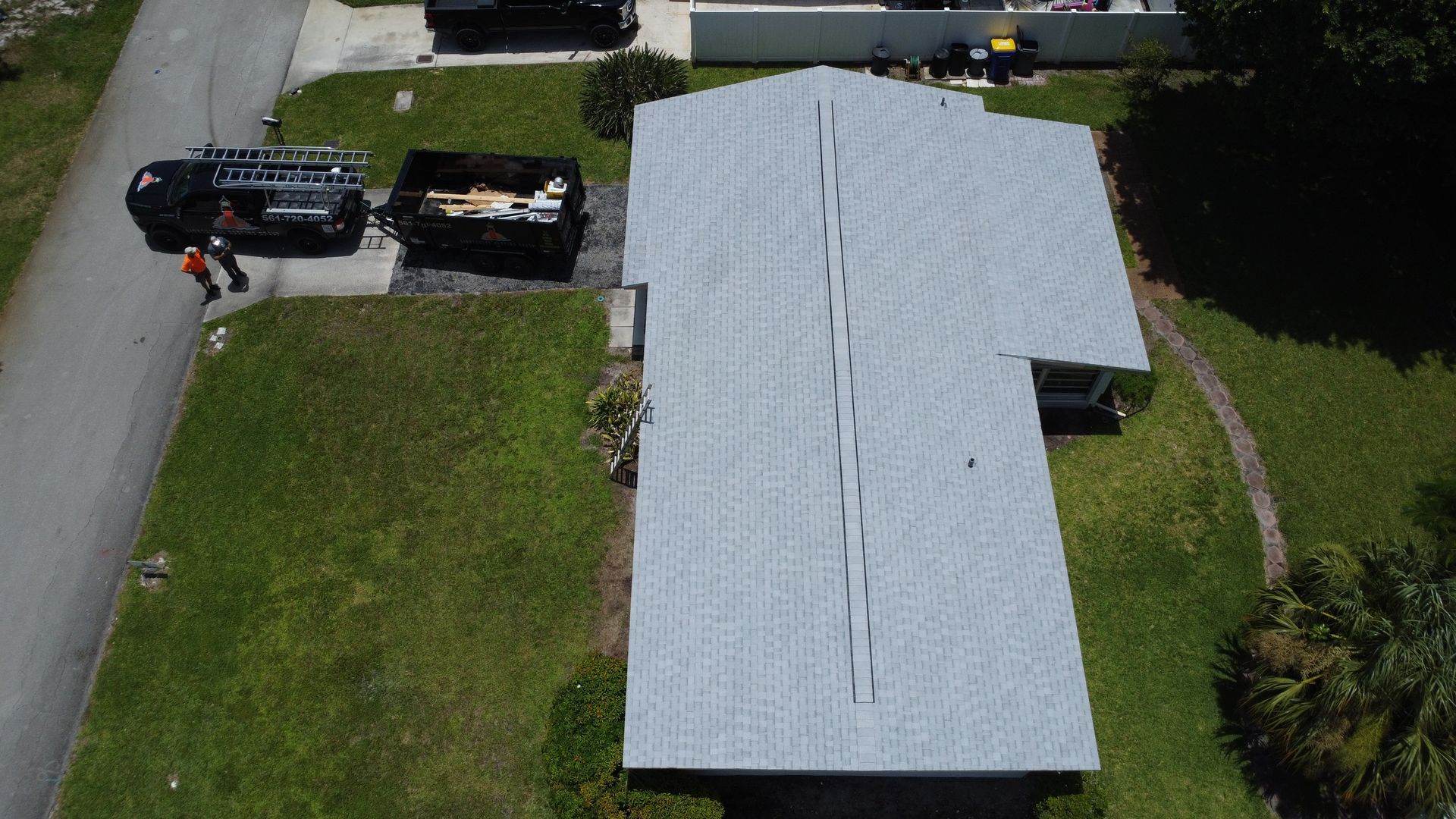 Aerial view of a house with a gray roof and a black truck parked in the driveway.