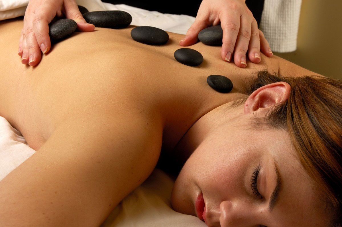 A woman is getting a massage with hot rocks on her back.