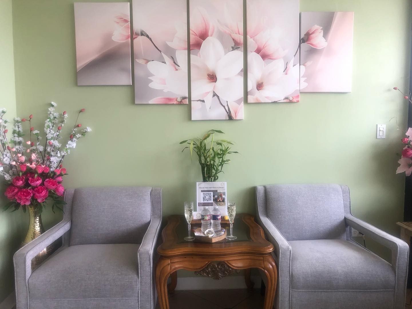 A waiting room with two chairs and a table with flowers on the wall.