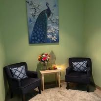 There is a painting of a peacock on the wall above the chairs.