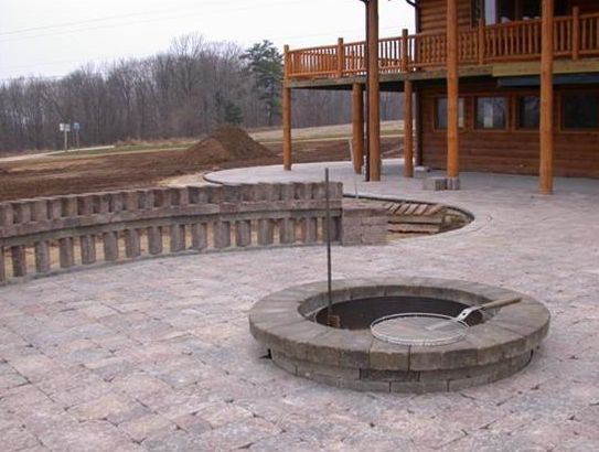 Stone courtyard with circular steps, built-in benches, and a wooden building in the background