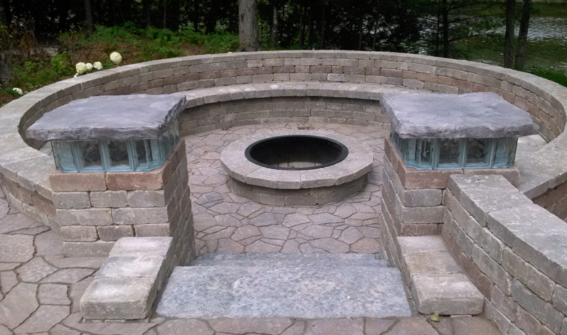 Stone outdoor fire pit with circular seating and a central opening in a landscaped yard