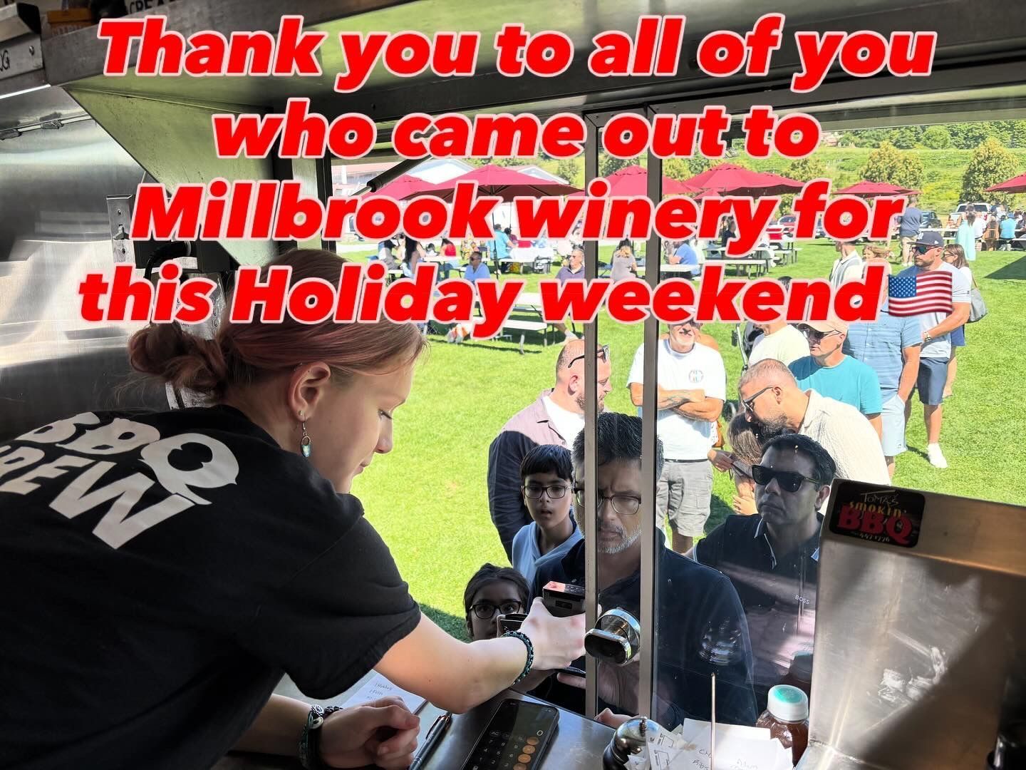 Person serving customers at a food truck at Millbrook winery on a holiday weekend. Crowd of people in background.