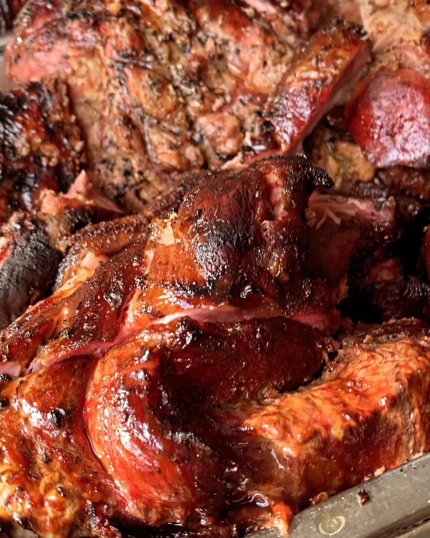 Close-up of cooked barbecue meat, glistening brown and red.