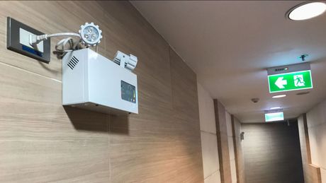 An emergency light is hanging on the wall of a hallway.