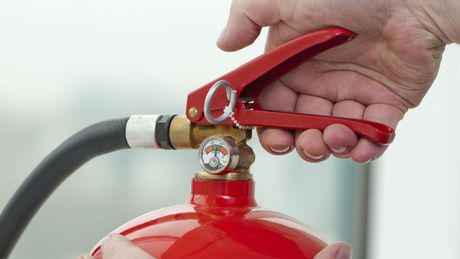 A person is holding a fire extinguisher in their hand.