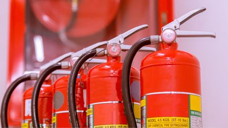 A row of red fire extinguishers are lined up in a row.