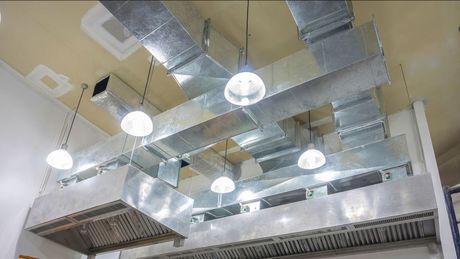 A kitchen with a lot of ducts and lights hanging from the ceiling.