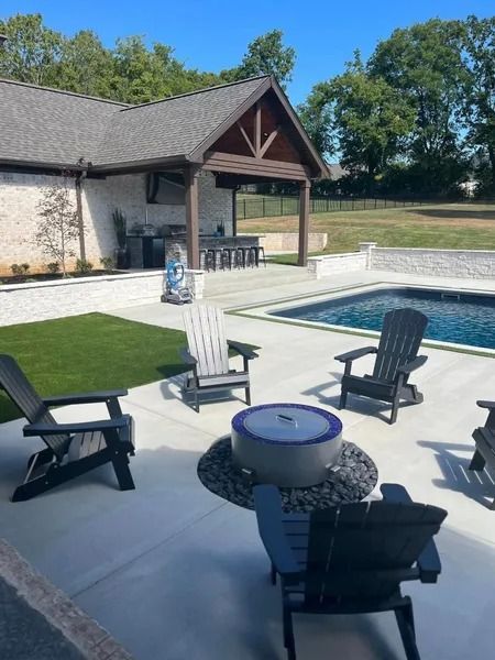 Outdoor patio with pool, fire pit, Adirondack chairs, and a kitchen area.