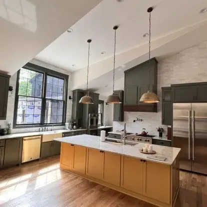 Modern kitchen with mustard island, olive cabinets, and wood accents.