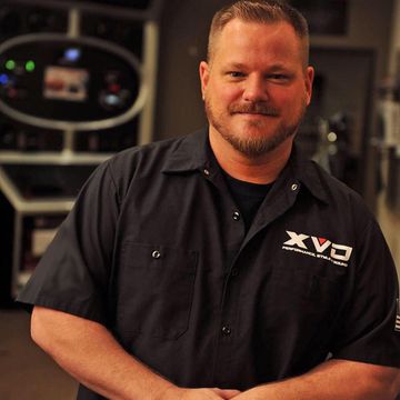A man with a beard wearing a black shirt that says xvc on it