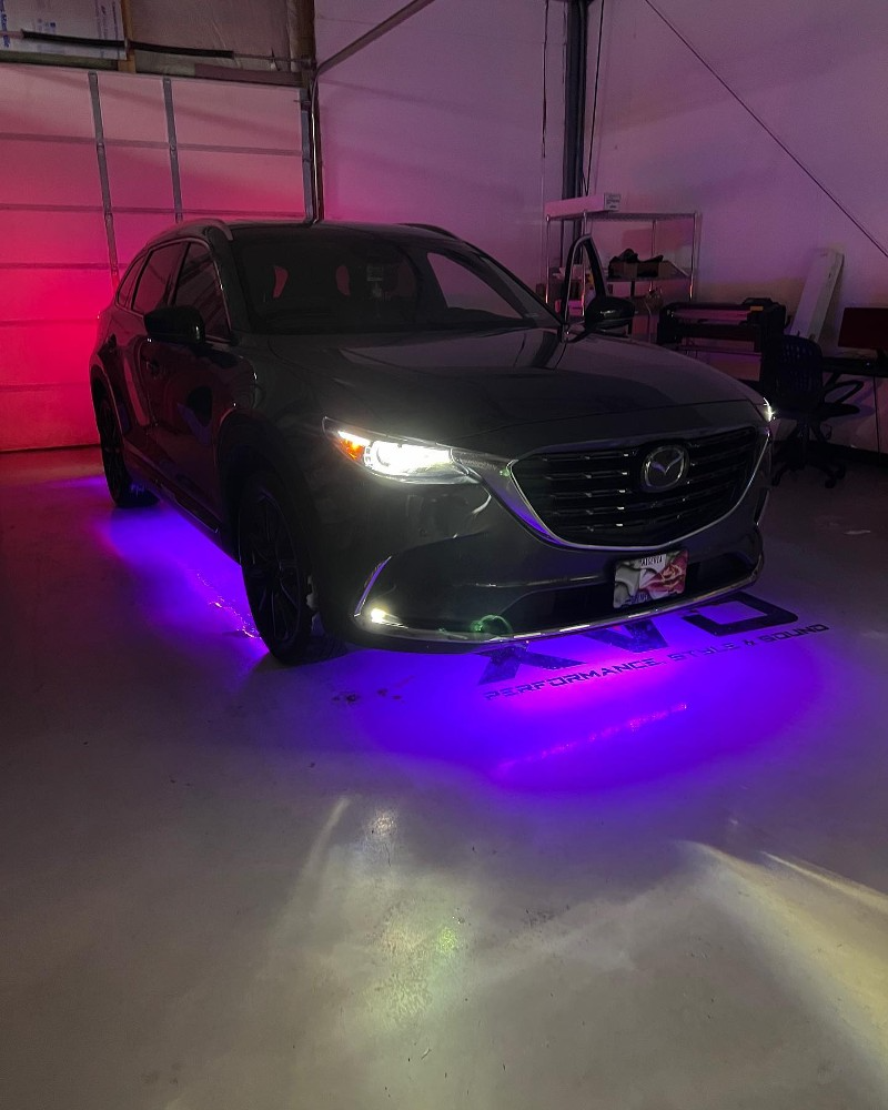 A car is parked in a garage with purple lights on it.
