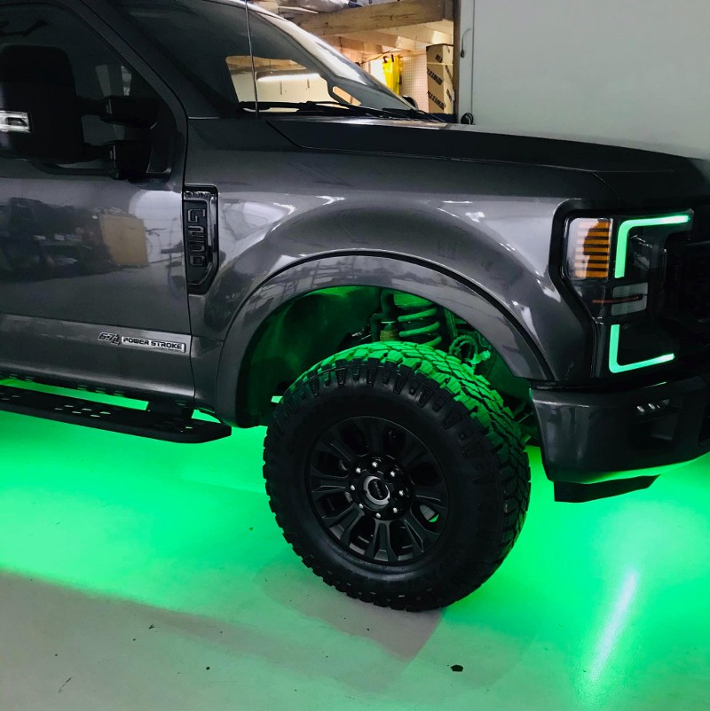 A gray truck with green lights underneath it