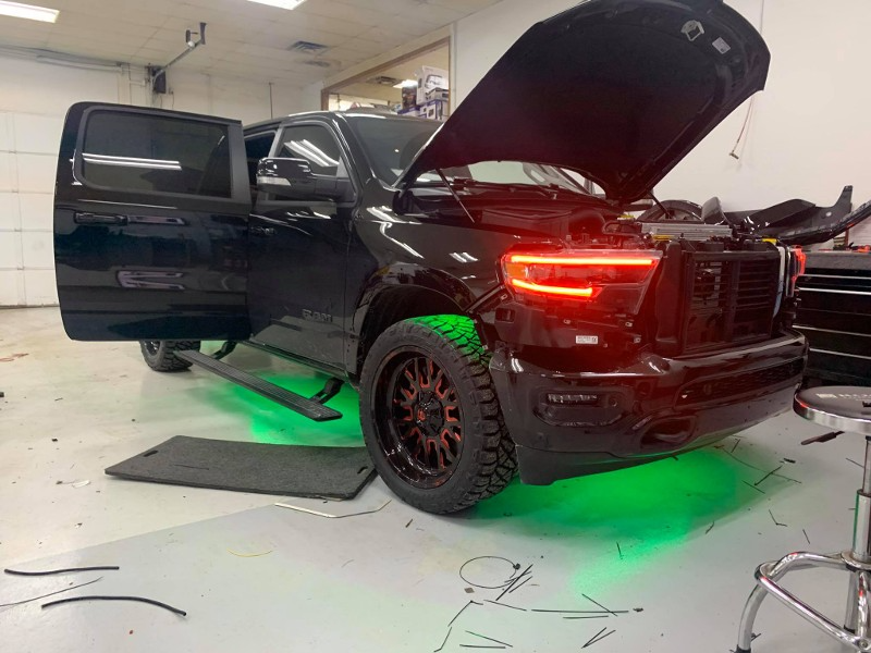 A black truck with the hood up is sitting in a garage.