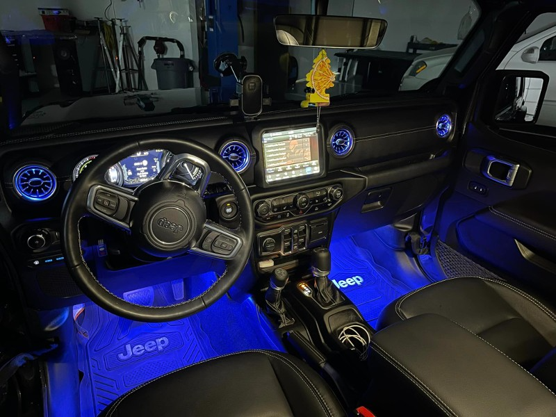 The interior of a jeep wrangler with blue lights.