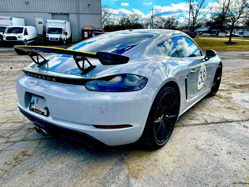 A white sports car with a spoiler on the back is parked in a parking lot.