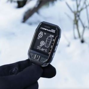 A person is holding a car alarm in their hand in the snow.