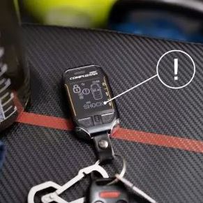 A remote control is sitting on top of a pair of keys on a table.