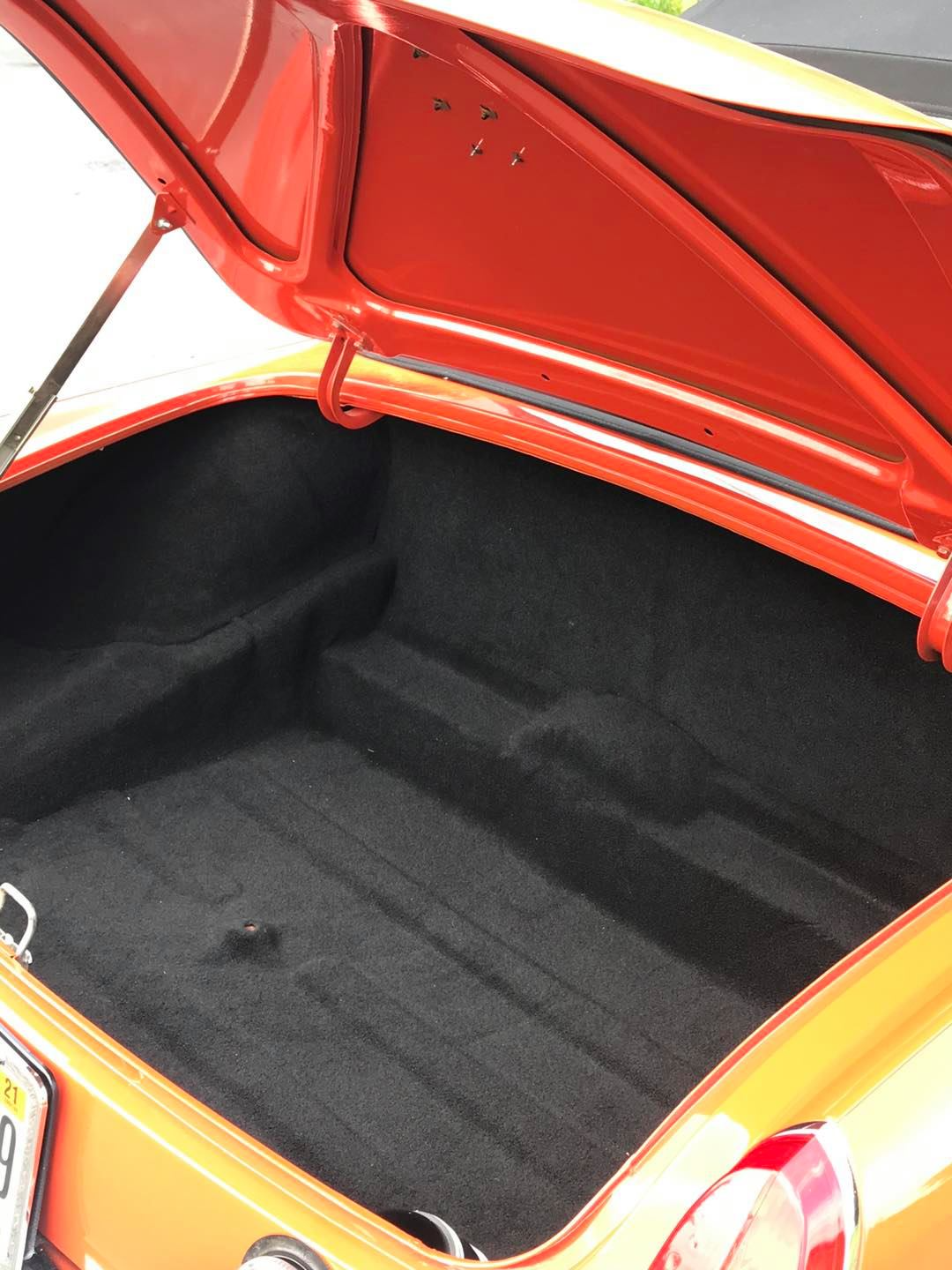 The trunk of an orange car with the hood up