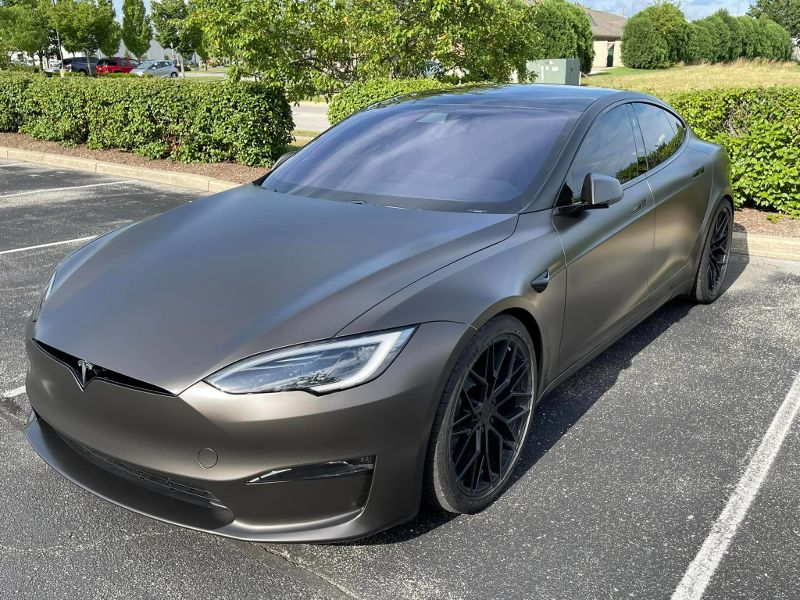 A black tesla model s is parked in a parking lot.