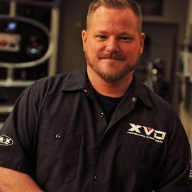 A man with a beard wearing a black shirt that says xvc on it