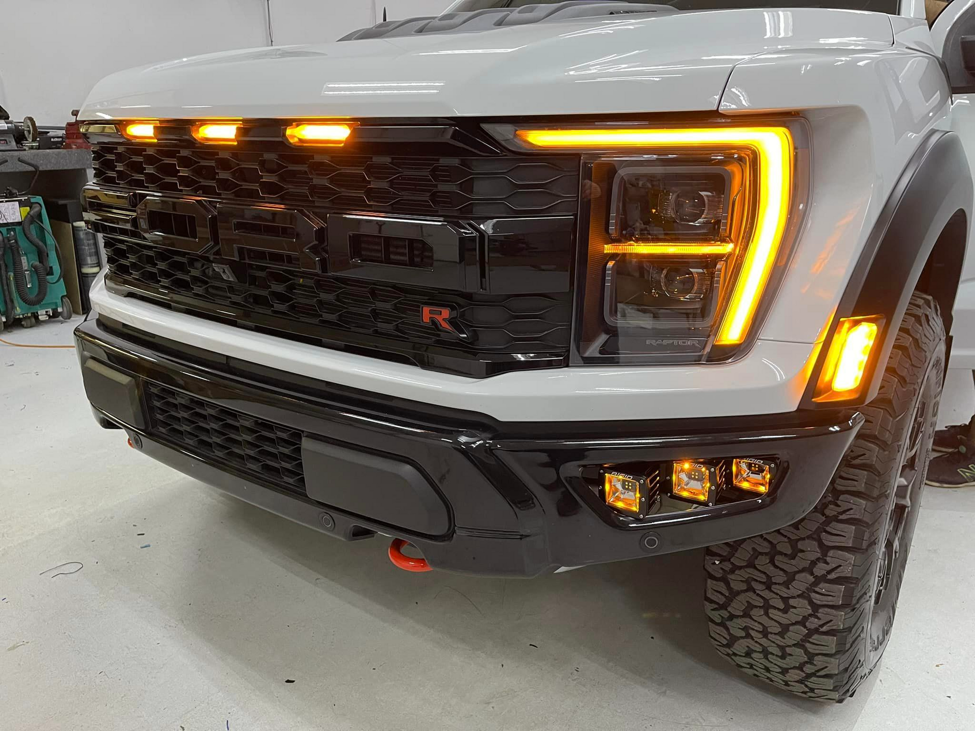 A white ford f150 raptor is parked in a garage.