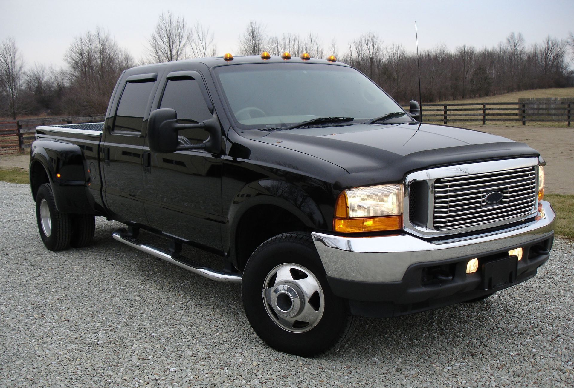 A black ford truck is parked in a gravel lot