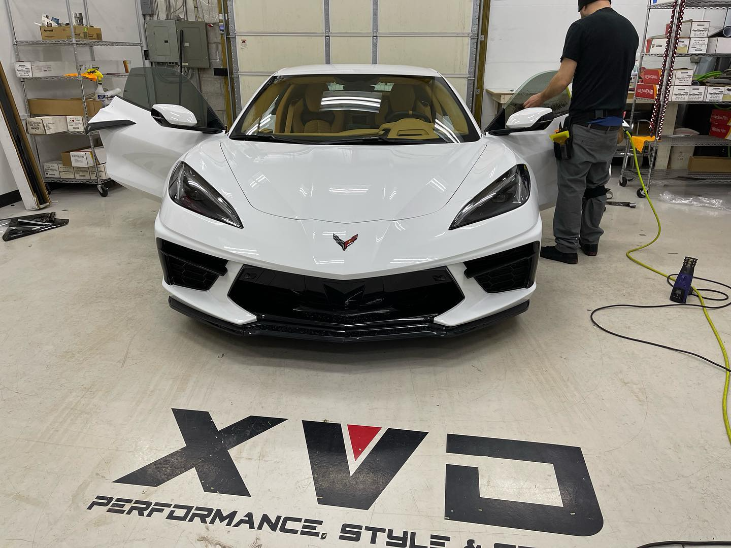 A man is working on a white sports car in a garage.