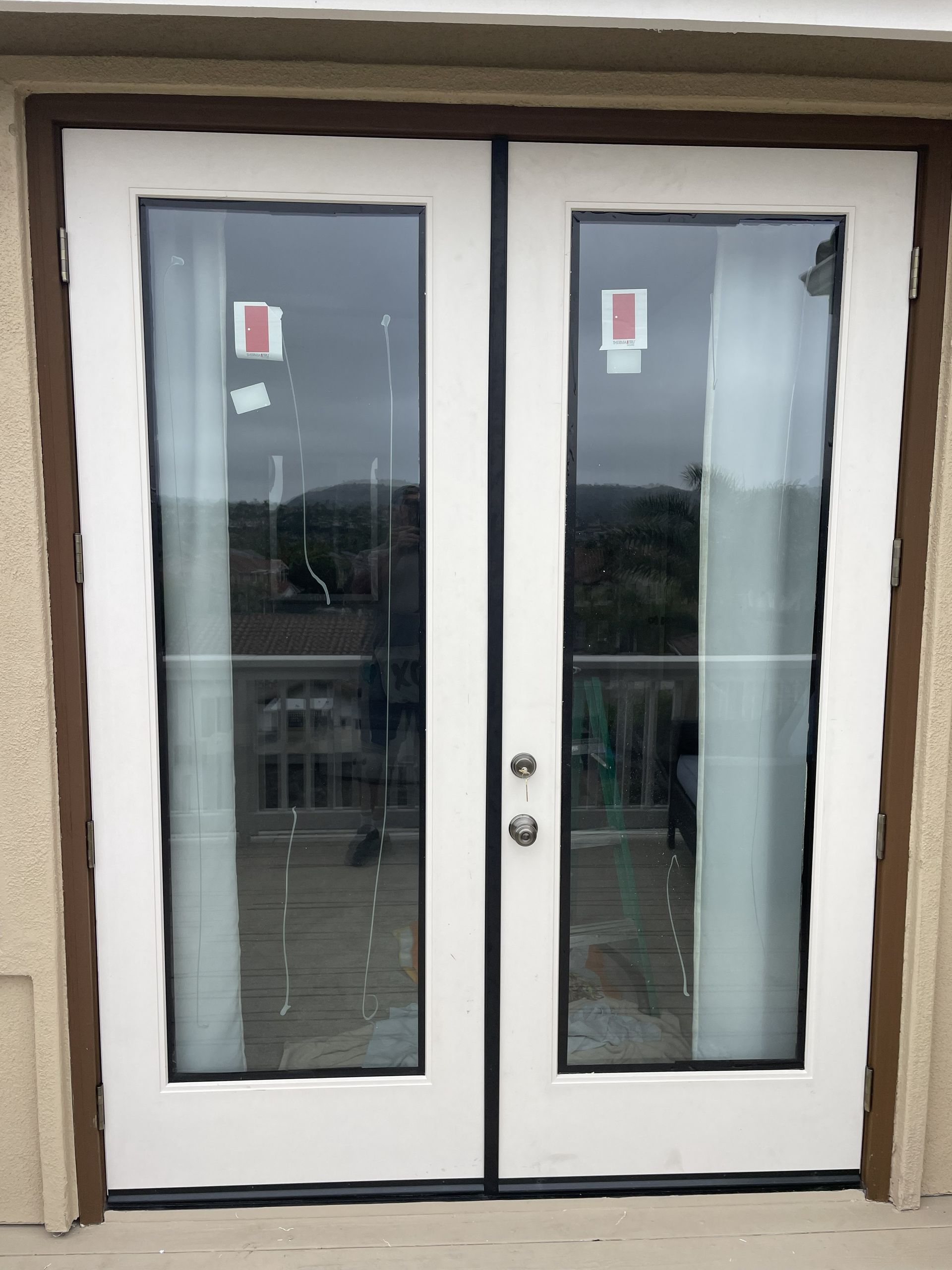 White double glass doors with black trim and round handles at a building entrance
