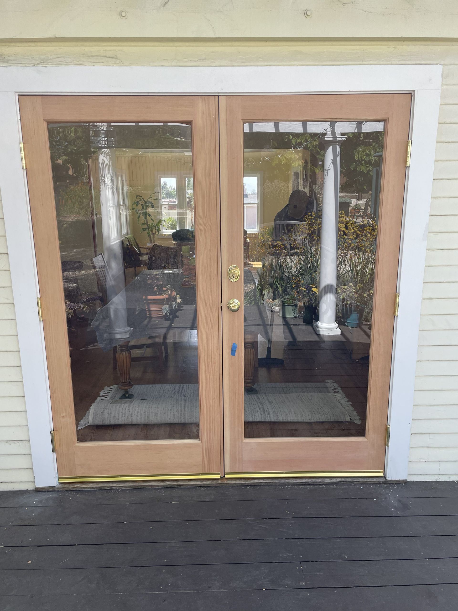 Wooden double glass front doors with black shutters and a screened porch behind them
