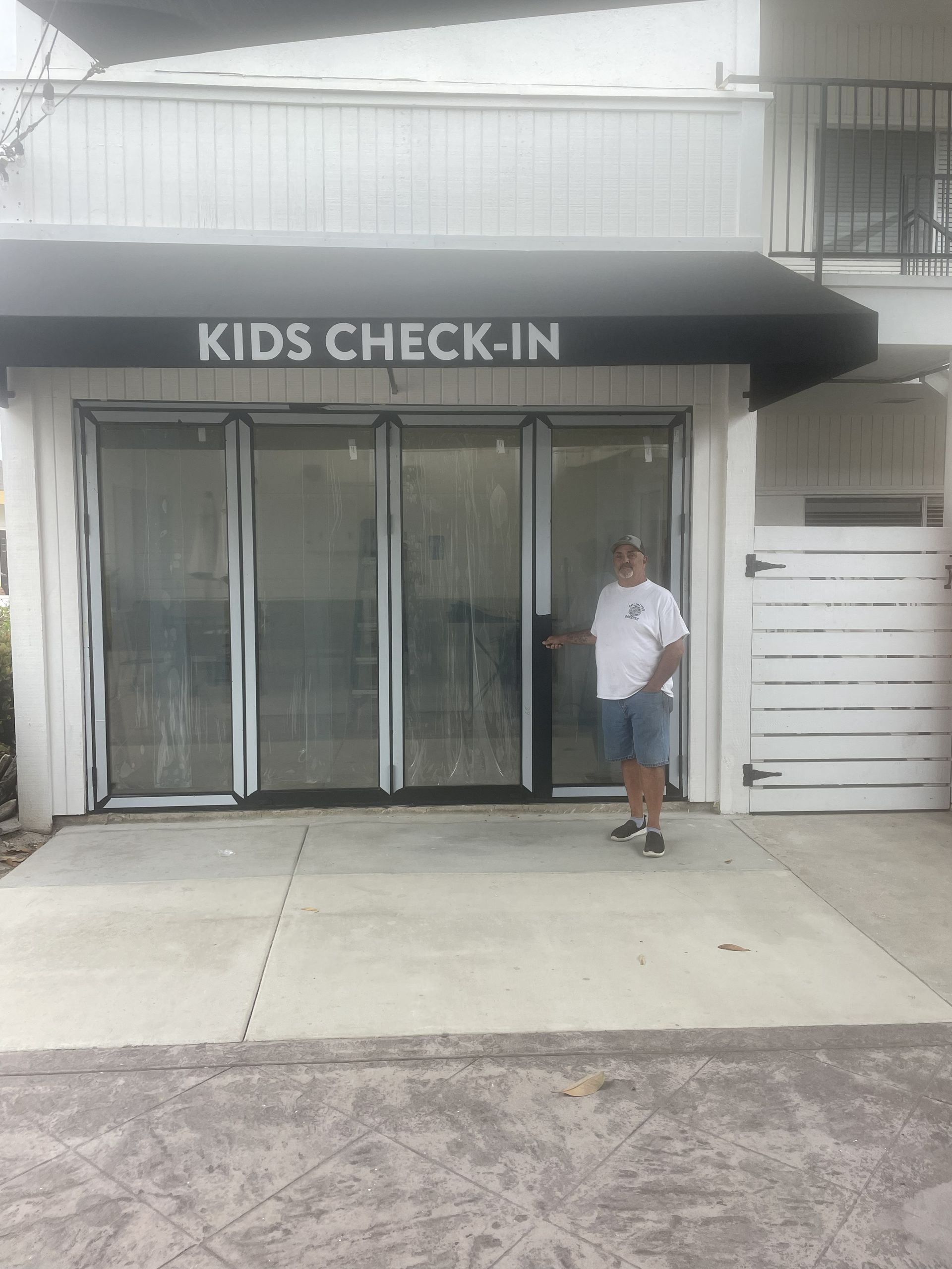 Kids check-in entrance with black awning and a person standing by the doors