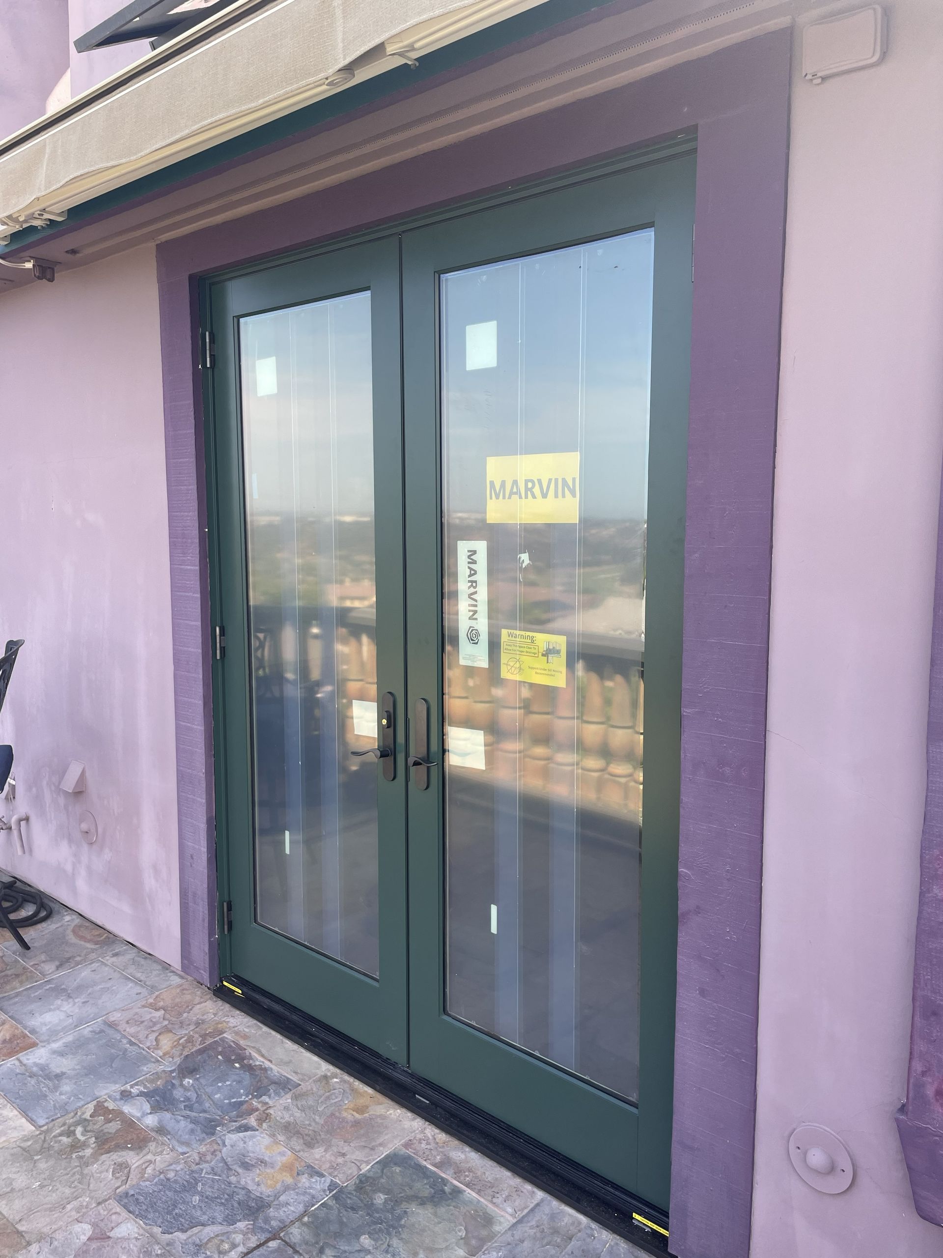 Green double glass doors with a yellow sign on a purple building exterior