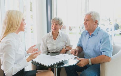 A man and a woman are sitting at a table talking to a woman.