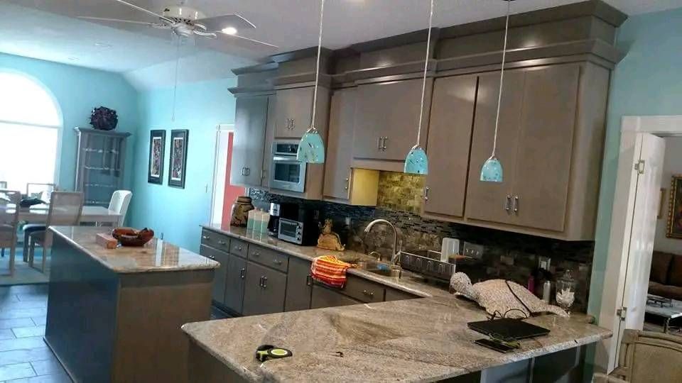 A kitchen with gray cabinets and granite counter tops.