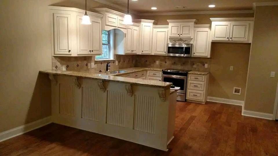 An empty kitchen with white cabinets and hardwood floors.