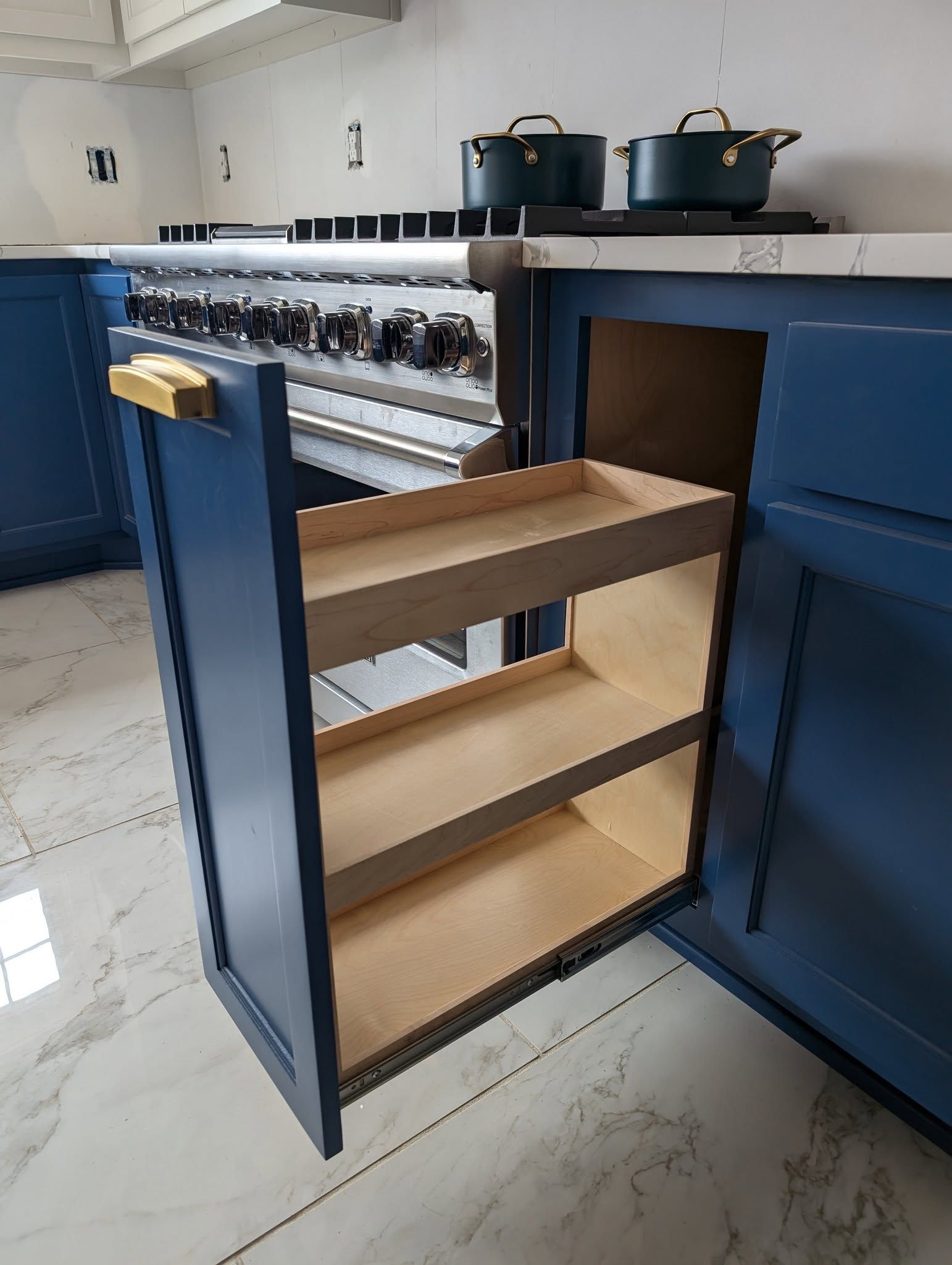 A kitchen with blue cabinets and a pull out spice rack.