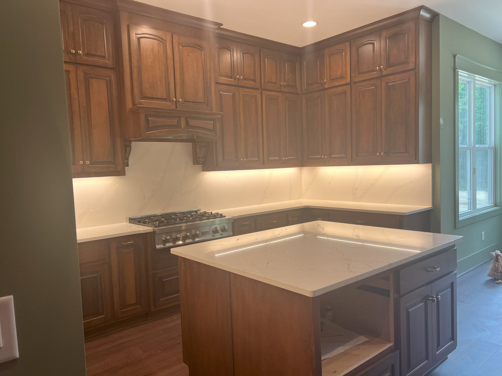 Brown wood kitchen cabinets with a white countertop and an island.