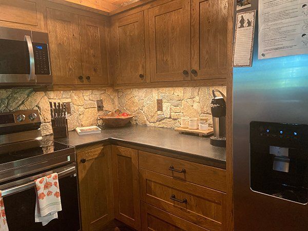 A kitchen with wooden cabinets , stainless steel appliances , a refrigerator and a microwave.