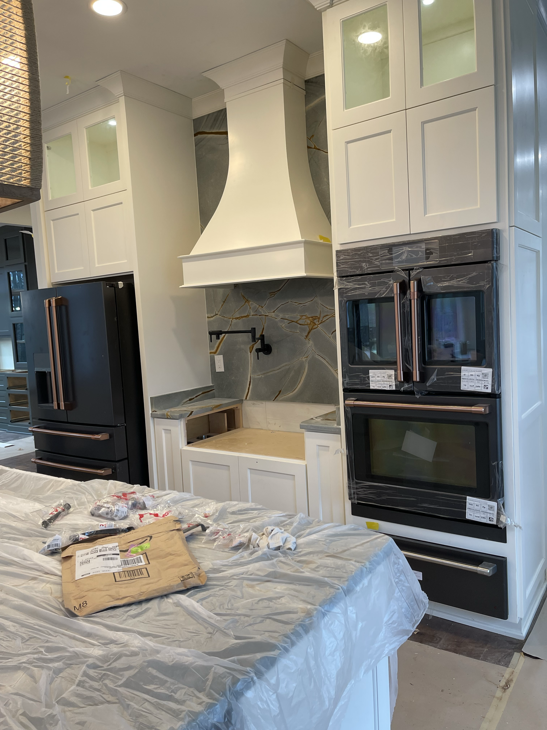 A kitchen with white cabinets and black appliances is being remodeled