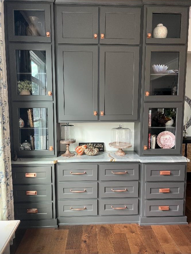 A kitchen with gray cabinets, drawers, and glass doors