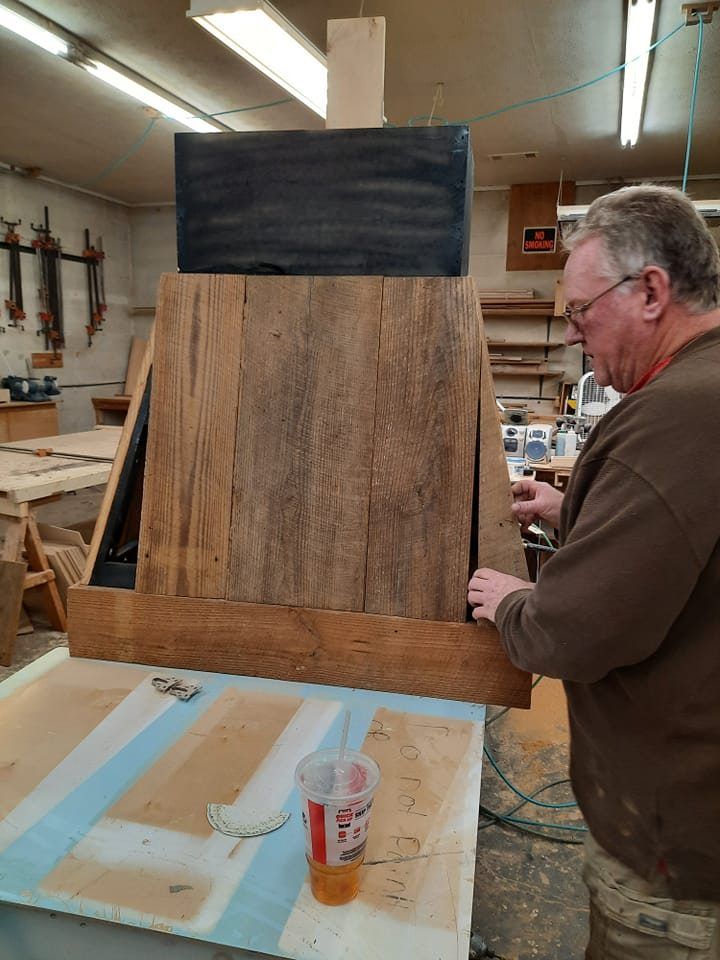 A man is working on a piece of wood in a workshop.