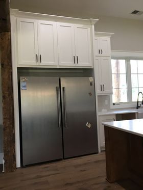 A kitchen with two stainless steel refrigerators and white cabinets.
