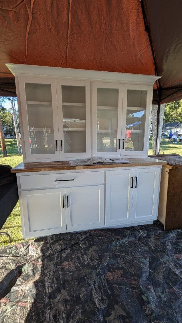 A white cabinet with glass doors is sitting on top of a rock.