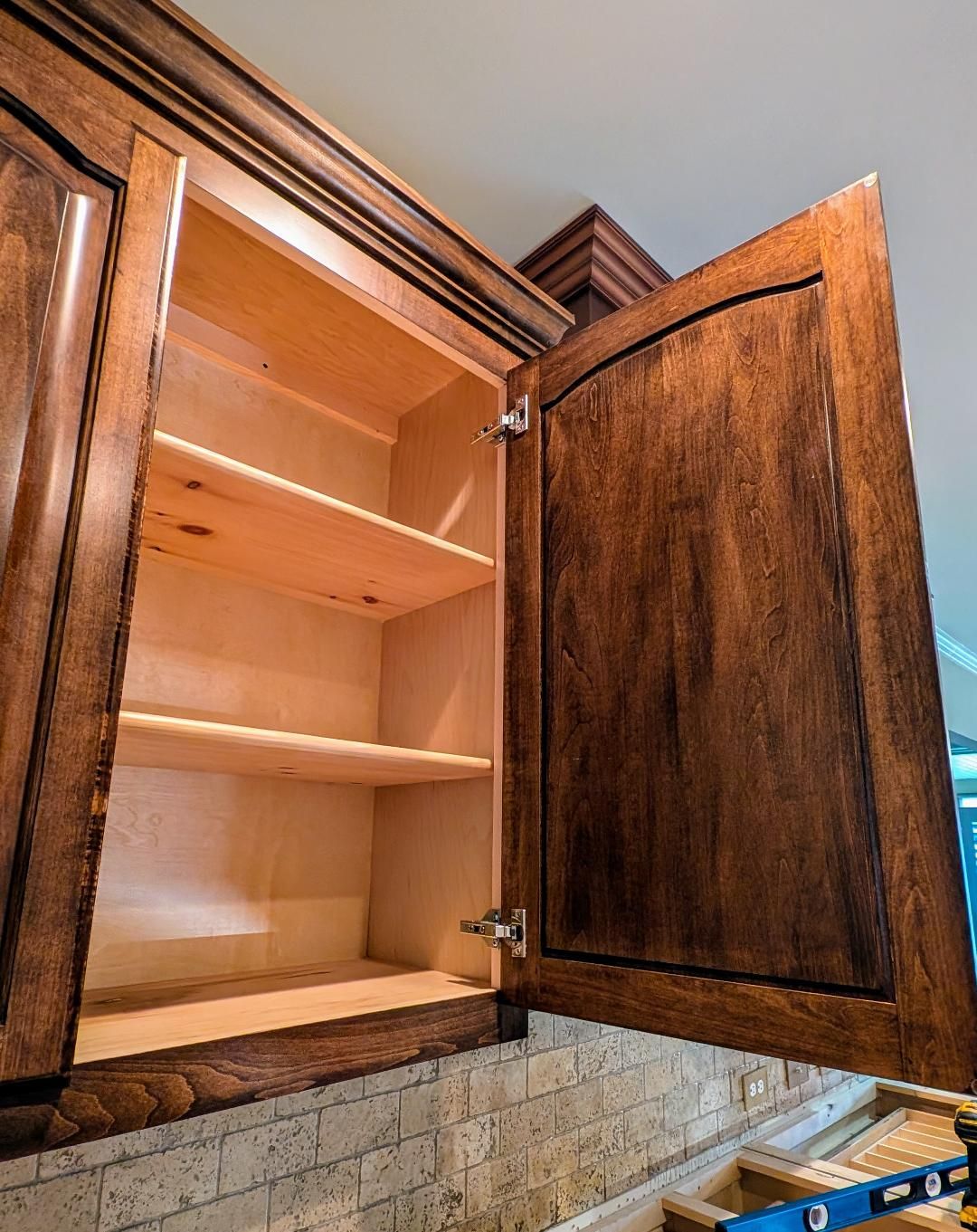 A kitchen cabinet with the door open and empty shelves.