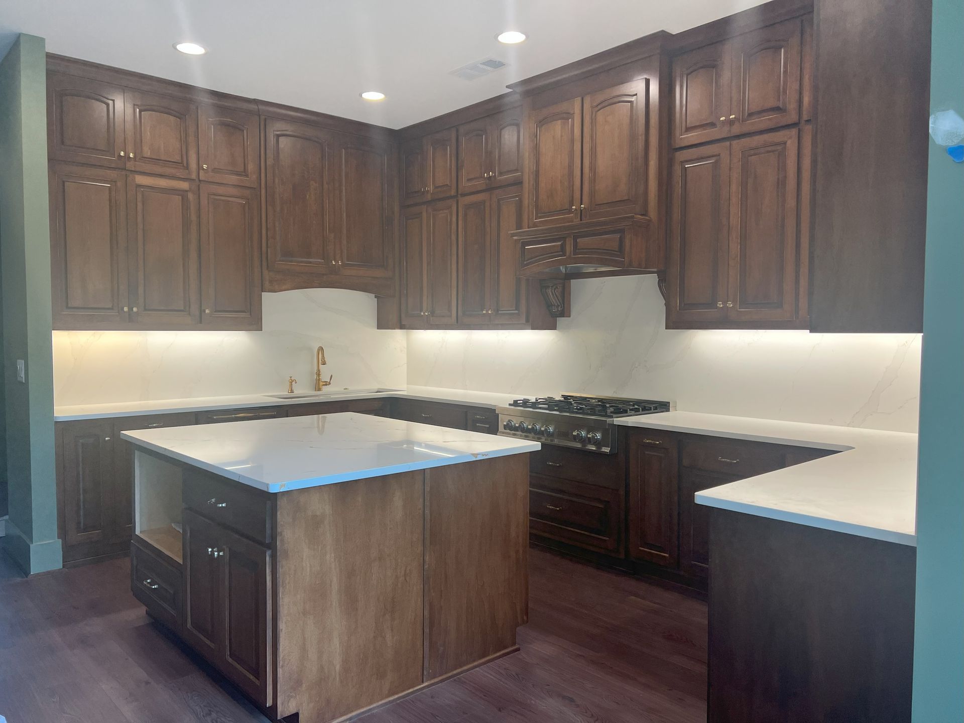 Dark wood kitchen with a large island and white countertops.