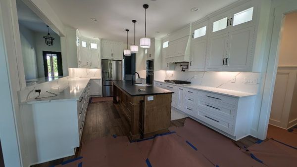A kitchen with white cabinets and a large island in the middle.