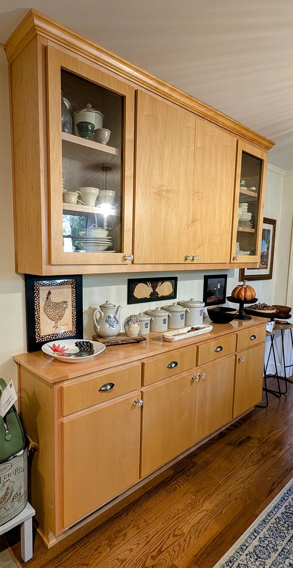A wooden cabinet with glass doors and drawers in a kitchen.