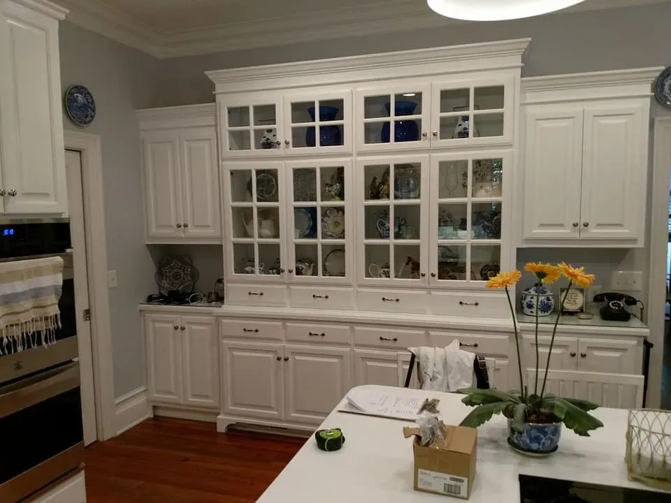 A kitchen with white cabinets and glass doors
